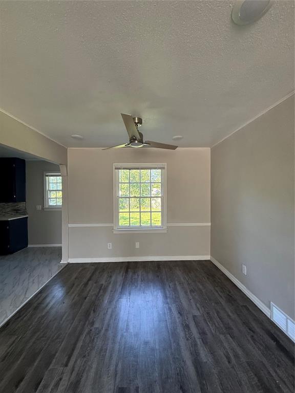 3208 N Roff Ave, Oklahoma City, OK 73112 - unfurnished living room featuring a textured ceiling, dark wood-type flooring, a ceiling fan, and baseboards