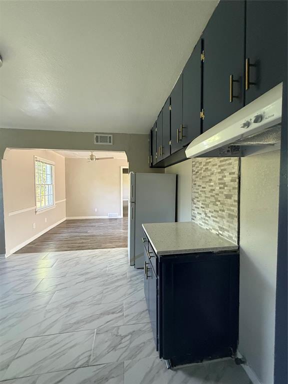 3208 N Roff Ave, Oklahoma City, OK 73112 - kitchen featuring under cabinet range hood, light marble finish floors, freestanding refrigerator, baseboards, and light countertops