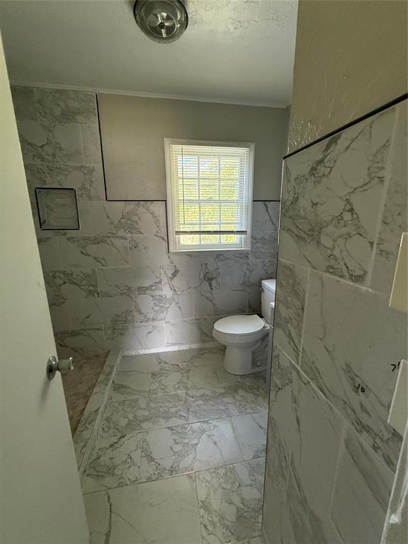 3208 N Roff Ave, Oklahoma City, OK 73112 - bathroom with toilet, a marble finish shower, crown molding, and marble look tile flooring