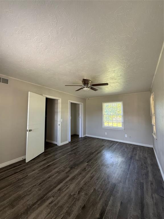 3208 N Roff Ave, Oklahoma City, OK 73112 - unfurnished bedroom featuring a textured ceiling, dark wood finished floors, baseboards, and a ceiling fan