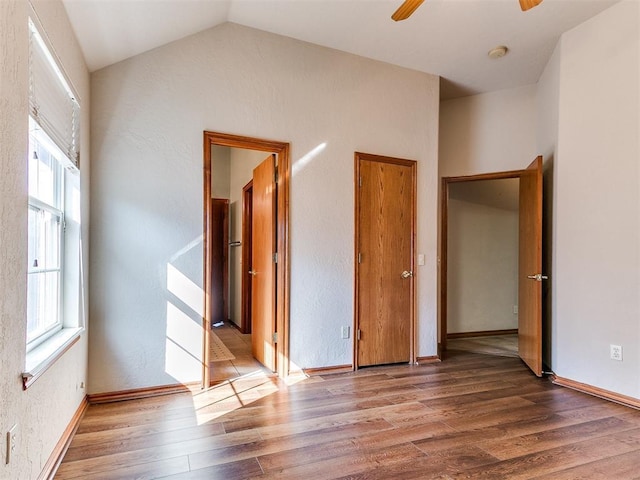 2508 Hamden Ave, Norman, OK 73069 - unfurnished bedroom featuring multiple windows, wood finished floors, baseboards, a textured wall, and vaulted ceiling