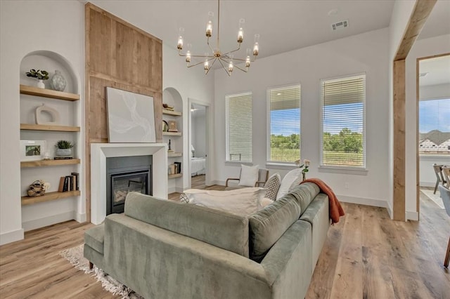5617 NW 155th St, Edmond, OK 73013 - living area with a glass covered fireplace, a chandelier, light wood-style floors, built in shelves, and baseboards
