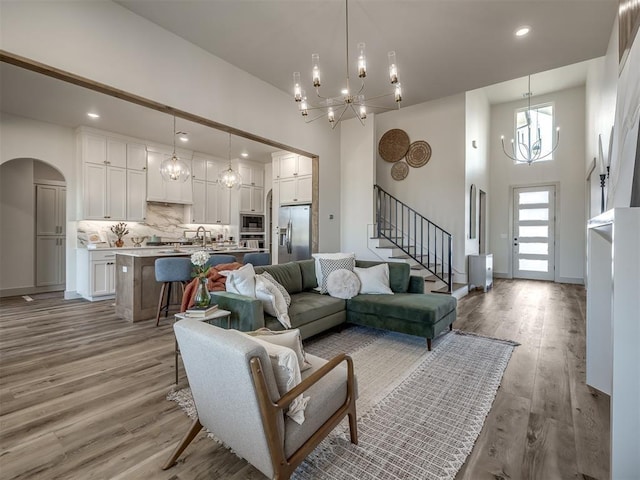 5617 NW 155th St, Edmond, OK 73013 - living area with a chandelier, arched walkways, a high ceiling, stairway, and wood finished floors