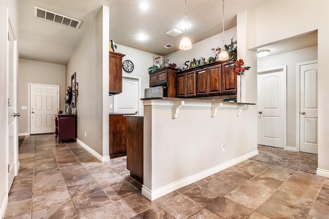 11444 NW 131st St, Piedmont, OK 73078 - kitchen featuring a breakfast bar, pendant lighting, baseboards, a peninsula, and dark brown cabinets