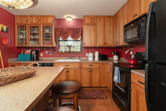 143 Robinson Ln, Ardmore, OK 73401 - kitchen with black appliances, a sink, a textured ceiling, a breakfast bar area, and light countertops