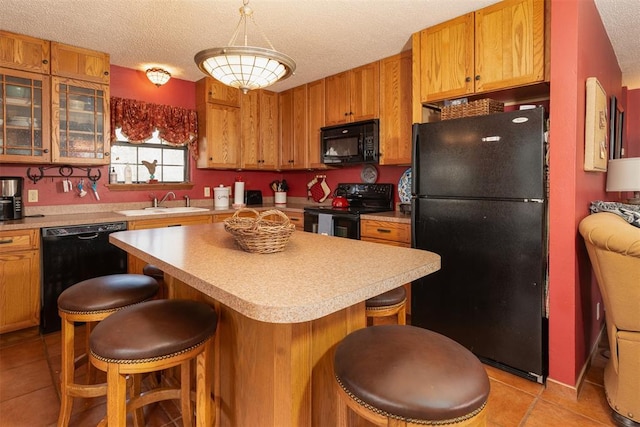 143 Robinson Ln, Ardmore, OK 73401 - kitchen featuring black appliances, a textured ceiling, light tile patterned flooring, light countertops, and a breakfast bar