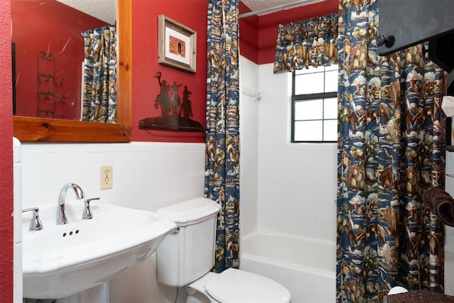 143 Robinson Ln, Ardmore, OK 73401 - full bathroom featuring toilet, shower / tub combo, a sink, wainscoting, and tile walls