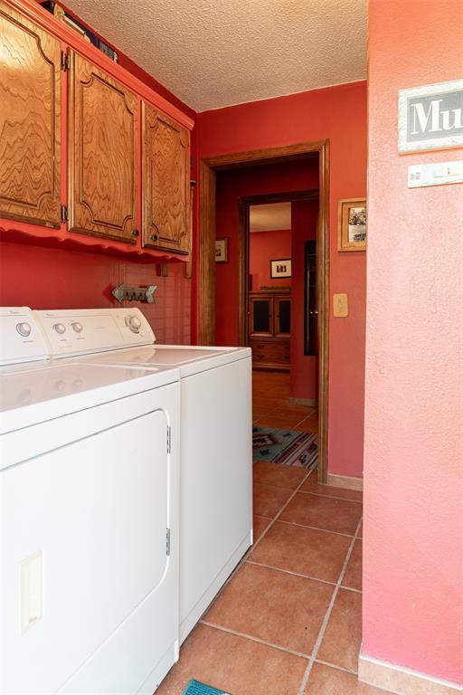 143 Robinson Ln, Ardmore, OK 73401 - laundry room with independent washer and dryer, cabinet space, light tile patterned flooring, and a textured ceiling