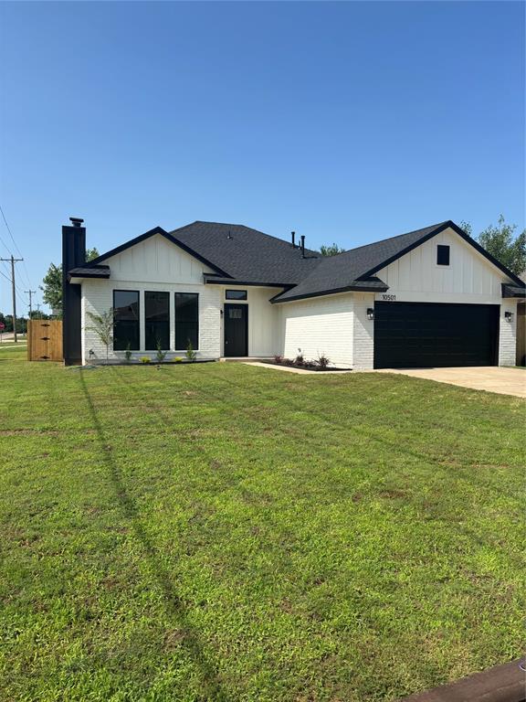 10501 Reiter Dr, Midwest City, OK 73130 - view of front of home featuring board and batten siding, an attached garage, a chimney, and a front yard