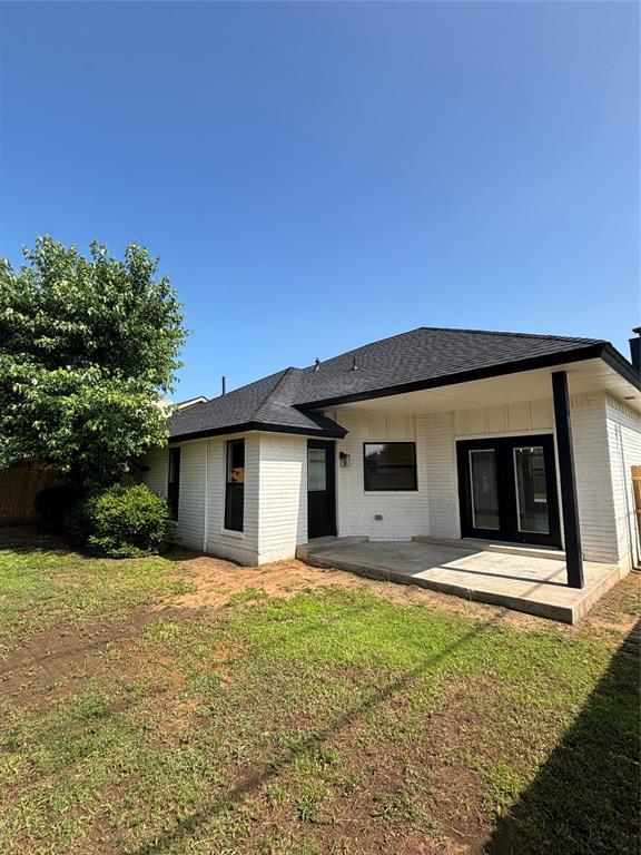 10501 Reiter Dr, Midwest City, OK 73130 - back of property with brick siding, a yard, a shingled roof, and a patio area