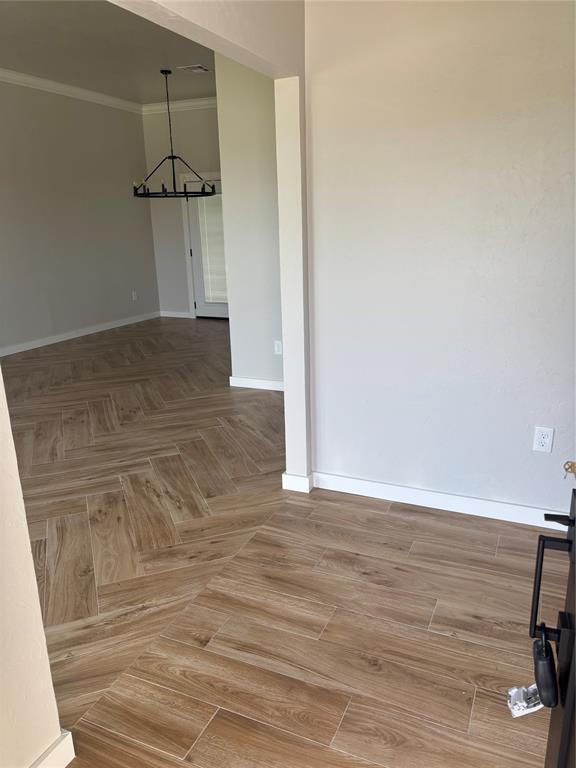 10501 Reiter Dr, Midwest City, OK 73130 - empty room with a chandelier, ornamental molding, and baseboards
