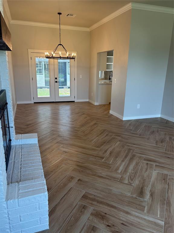 10501 Reiter Dr, Midwest City, OK 73130 - unfurnished living room featuring a chandelier, baseboards, a fireplace, and ornamental molding