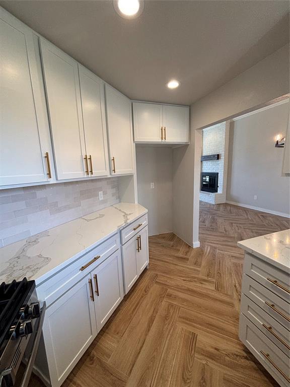 10501 Reiter Dr, Midwest City, OK 73130 - kitchen with stainless steel gas range oven, white cabinets, light stone counters, and recessed lighting