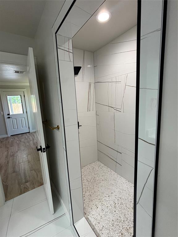10501 Reiter Dr, Midwest City, OK 73130 - bathroom with tiled shower, wood finished floors, and baseboards