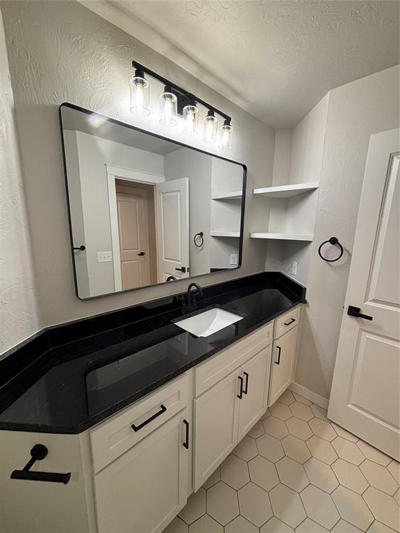 10501 Reiter Dr, Midwest City, OK 73130 - bathroom featuring a textured wall, tile patterned floors, vanity, and a textured ceiling