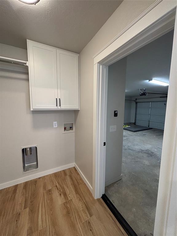10501 Reiter Dr, Midwest City, OK 73130 - laundry room featuring cabinet space, baseboards, hookup for a washing machine, and wood finished floors
