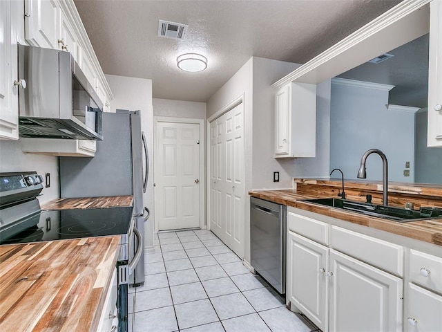 105 Taos, Edmond, OK 73013 - kitchen with wood counters, appliances with stainless steel finishes, white cabinets, a textured ceiling, and crown molding