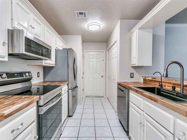 105 Taos, Edmond, OK 73013 - kitchen with stainless steel appliances, wood counters, white cabinetry, and a textured ceiling