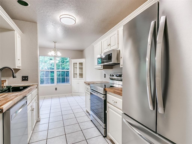 105 Taos, Edmond, OK 73013 - kitchen with appliances with stainless steel finishes, a textured ceiling, wood counters, white cabinetry, and a chandelier