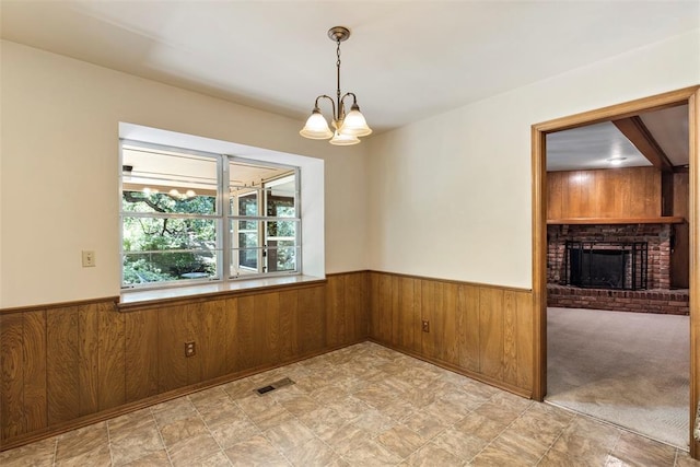 1112 E 11th St, Edmond, OK 73034 - unfurnished dining area featuring wood walls, a wainscoted wall, a chandelier, a brick fireplace, and stone finish flooring