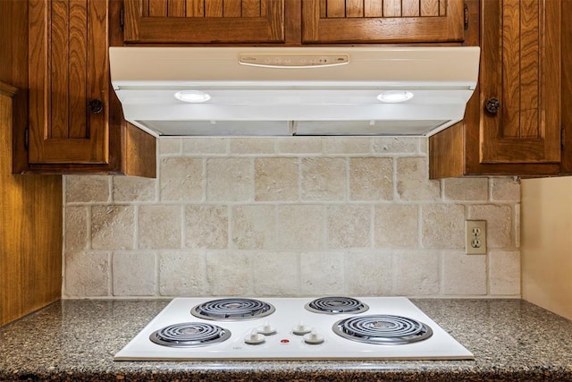 1112 E 11th St, Edmond, OK 73034 - kitchen with under cabinet range hood, white electric stovetop, brown cabinetry, and dark countertops