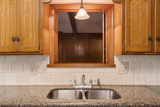 1112 E 11th St, Edmond, OK 73034 - kitchen featuring a sink, brown cabinetry, backsplash, and dark stone countertops