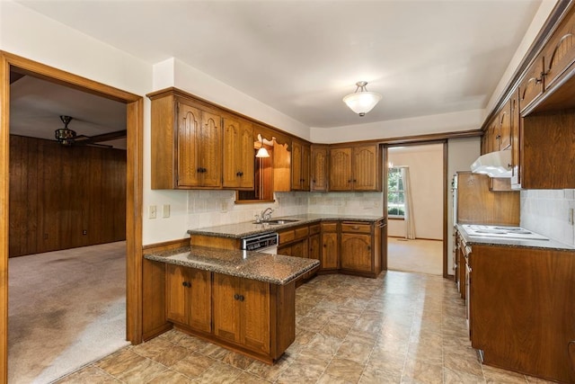 1112 E 11th St, Edmond, OK 73034 - kitchen featuring a sink, a peninsula, a ceiling fan, tasteful backsplash, and wooden walls