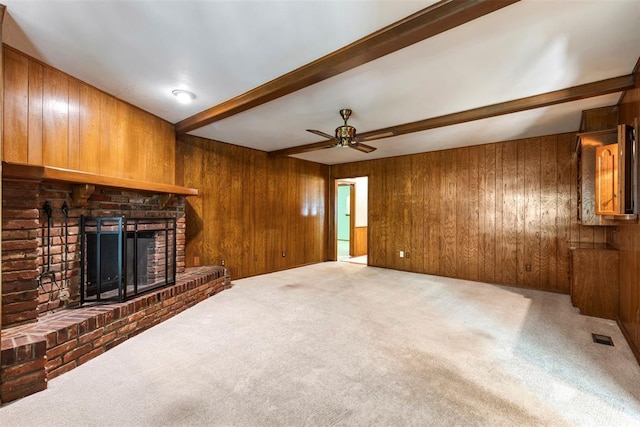 1112 E 11th St, Edmond, OK 73034 - unfurnished living room featuring wooden walls, beamed ceiling, carpet floors, a brick fireplace, and a ceiling fan