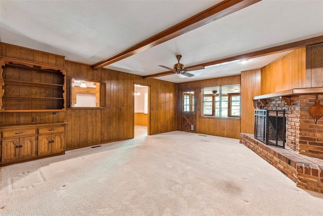 1112 E 11th St, Edmond, OK 73034 - unfurnished living room with beam ceiling, wooden walls, a fireplace, light colored carpet, and ceiling fan