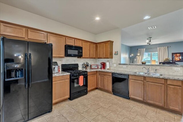 2721 Demotte Dr, Yukon, OK 73099 - kitchen with black appliances, a sink, decorative backsplash, light stone countertops, and brown cabinetry