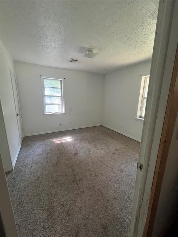 1209 Jefferson St, Seminole, OK 74868 - empty room with a textured ceiling, dark colored carpet, and baseboards