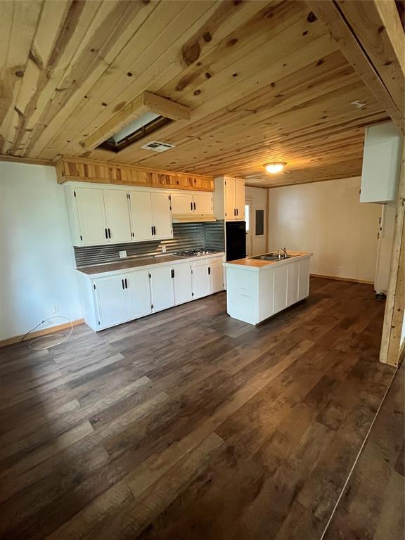 1209 Jefferson St, Seminole, OK 74868 - kitchen featuring white cabinets, a sink, dark wood-style floors, and an island with sink