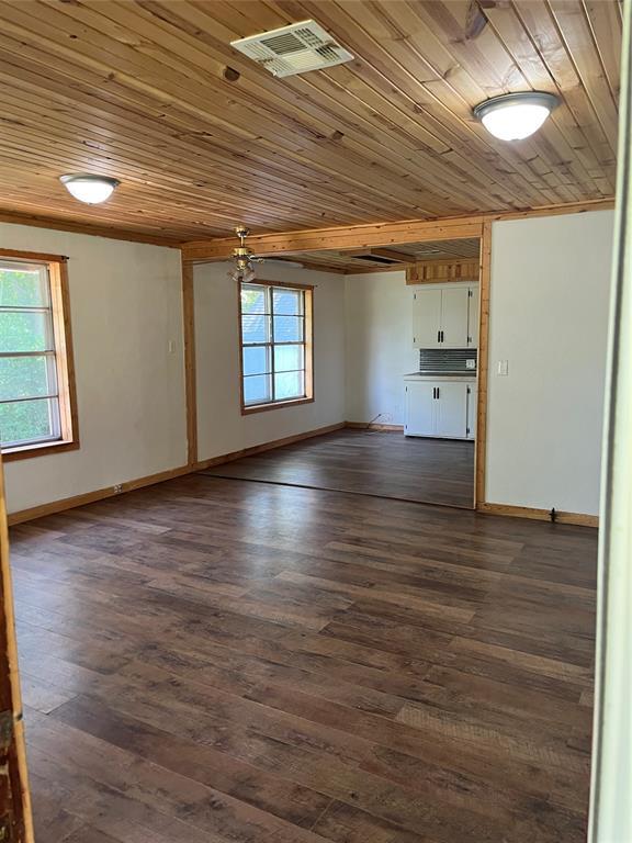 1209 Jefferson St, Seminole, OK 74868 - unfurnished living room featuring wooden ceiling, baseboards, and dark wood-style floors