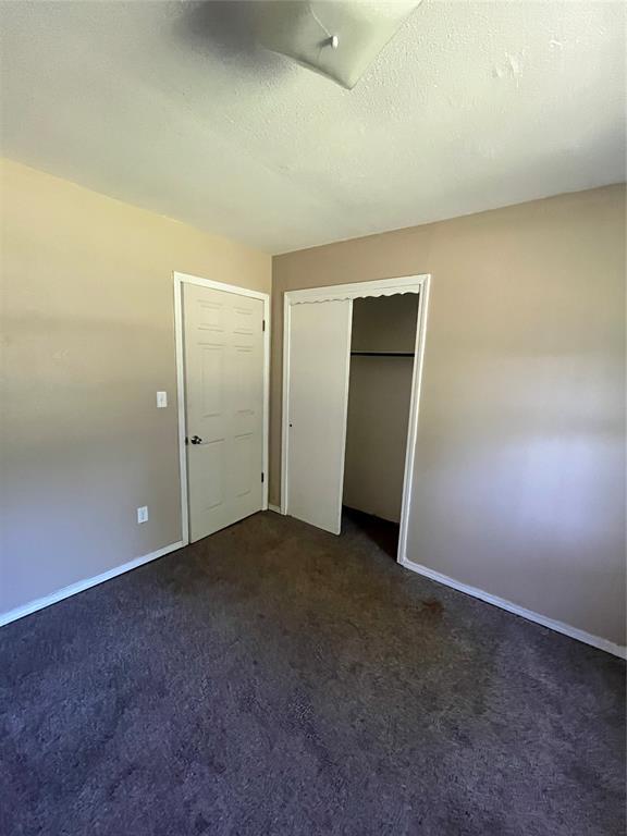 1209 Jefferson St, Seminole, OK 74868 - unfurnished bedroom with dark colored carpet, baseboards, and a closet