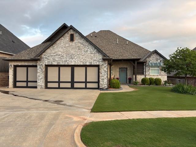 3328 NW 188th St, Edmond, OK 73012 - view of front of home with stone siding, a garage, a front lawn, concrete driveway, and a shingled roof