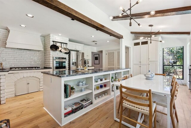 2241 NW 56th St, Oklahoma City, OK 73112 - kitchen featuring a chandelier, stainless steel appliances, beamed ceiling, open shelves, and premium range hood