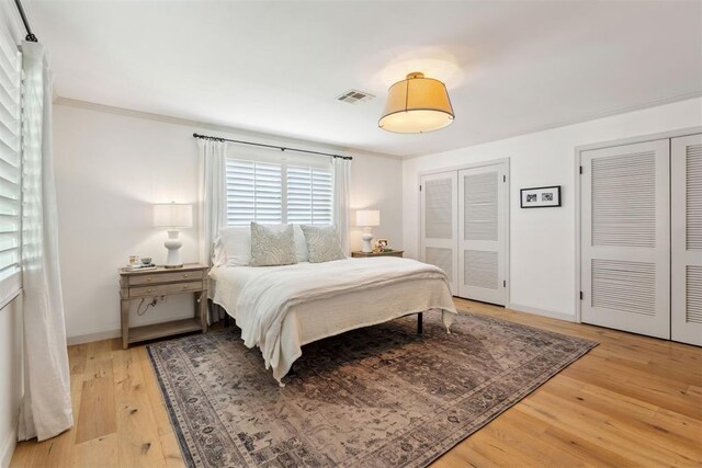 2241 NW 56th St, Oklahoma City, OK 73112 - bedroom featuring multiple closets, light wood-style floors, baseboards, and ornamental molding