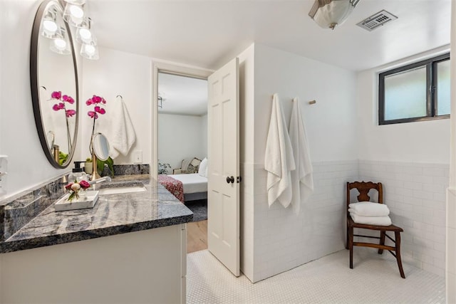 2241 NW 56th St, Oklahoma City, OK 73112 - full bathroom with vanity, ensuite bathroom, tile walls, tile patterned flooring, and wainscoting
