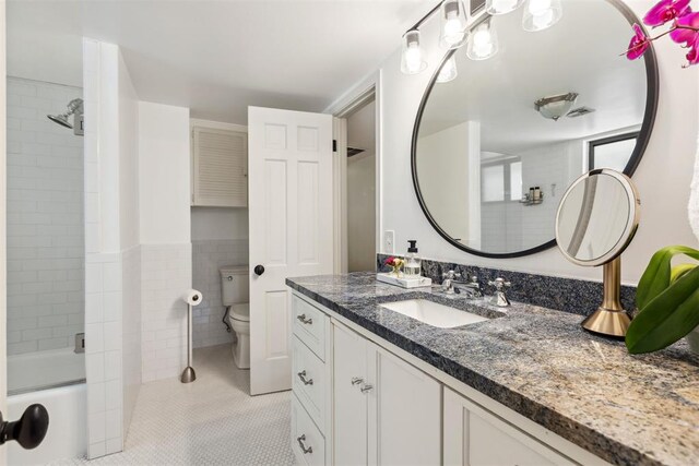 2241 NW 56th St, Oklahoma City, OK 73112 - bathroom featuring vanity, toilet, tile patterned floors, tile walls, and washtub / shower combination