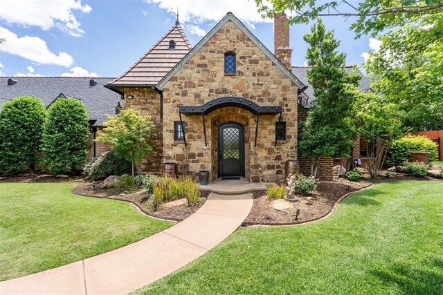 1324 NW 157th St, Edmond, OK 73013 - tudor home with stone siding, a chimney, and a front lawn