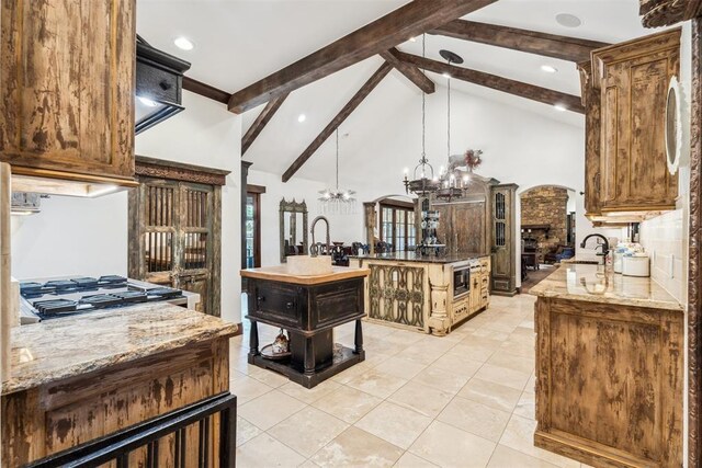 1324 NW 157th St, Edmond, OK 73013 - kitchen featuring a sink, a chandelier, beam ceiling, high vaulted ceiling, and light stone counters
