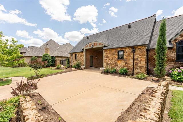 1324 NW 157th St, Edmond, OK 73013 - french country home featuring roof with shingles, a front yard, brick siding, and stone siding