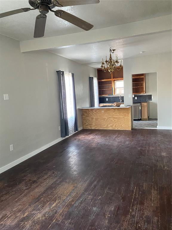 640 SE 20th St, Oklahoma City, OK 73129 - unfurnished living room with hardwood / wood-style floors, baseboards, a chandelier, ceiling fan, and beamed ceiling