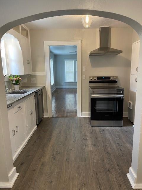 306 E Hughbert St, Norman, OK 73069 - kitchen featuring appliances with stainless steel finishes, wall chimney exhaust hood, arched walkways, a sink, and dark wood finished floors