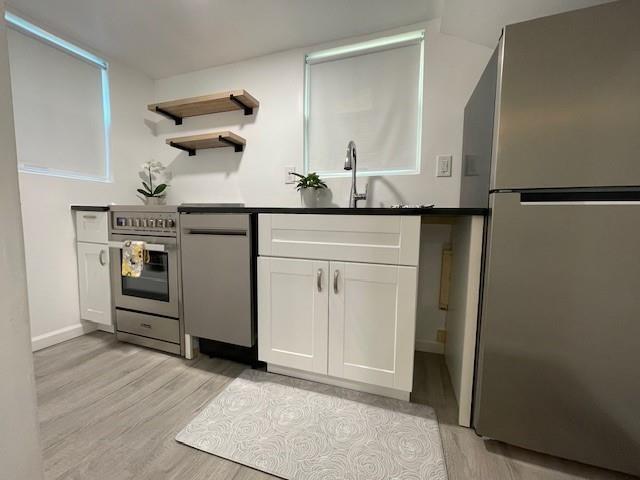 306 E Hughbert St, Norman, OK 73069 - kitchen featuring stainless steel appliances, light wood-style flooring, white cabinets, a sink, and baseboards