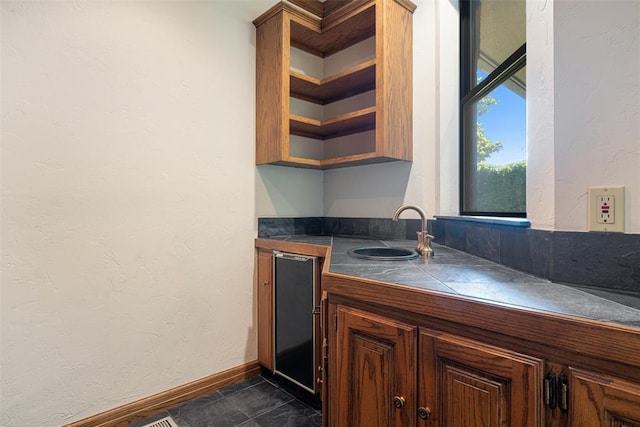 1409 Glenbrook Ter, Nichols Hills, OK 73116 - kitchen with a sink, tile countertops, baseboards, open shelves, and a textured wall