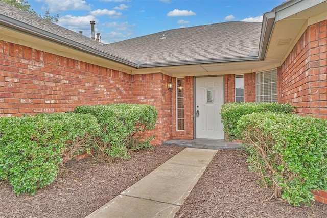 1101 Wendy Ln, Altus, OK 73521 - view of exterior entry featuring brick siding and roof with shingles