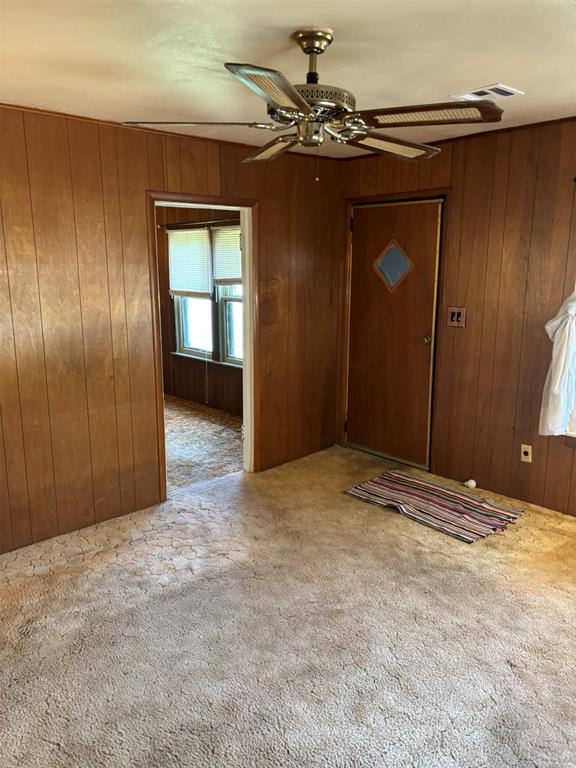 316 N Crenshaw St, Wayne, OK 73080 - foyer with wood walls, carpet, and a ceiling fan