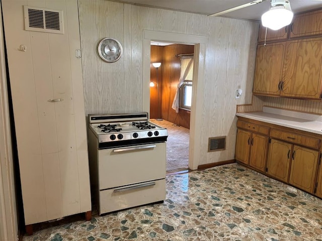 316 N Crenshaw St, Wayne, OK 73080 - kitchen featuring white gas range oven, a ceiling fan, brown cabinetry, light countertops, and stone finish flooring