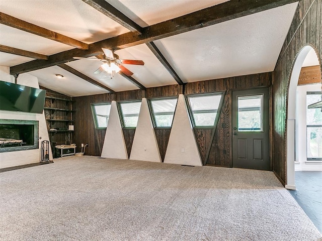 10109 Bison Cir, Yukon, OK 73099 - unfurnished living room with healthy amount of natural light, ceiling fan, carpet, wooden walls, and arched walkways
